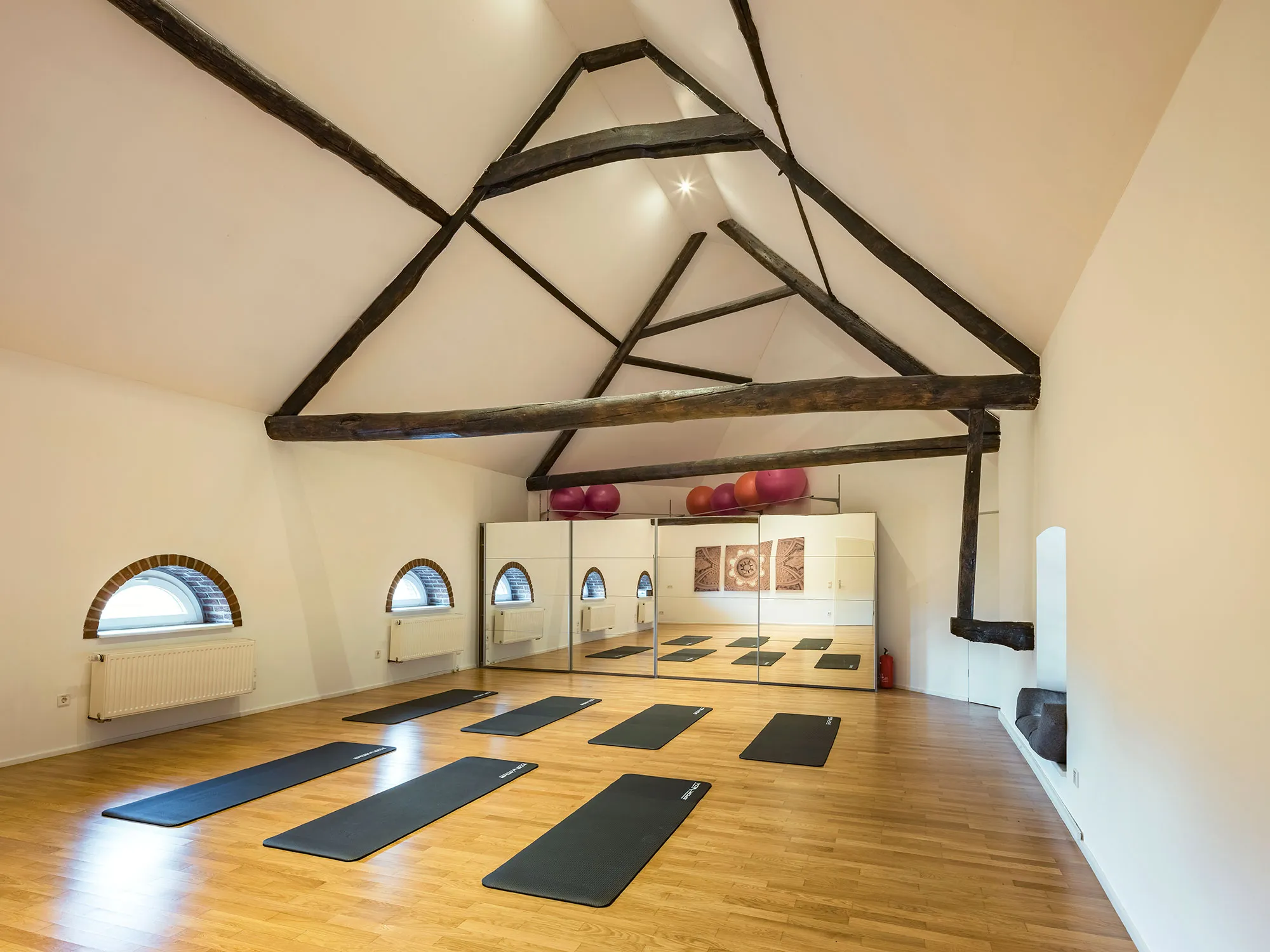 Der helle Yogaraum der Auszeit mit Matten auf dem Holzboden